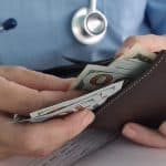 A veterinarian earning ProSal counts money in his wallet.