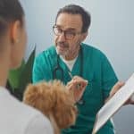 a veterinary professional man talks to a female pet owner holding her dog
