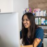 happy female veterinary professional works on a computer